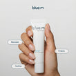 Load image into Gallery viewer, A hand holding a white tube of blue m oral gel, with text callouts reading 'Recovers', 'Soothes', and 'Protects' on a light gray background.
