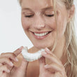 Load image into Gallery viewer, Woman holding a clear dental aligner filled with blue®m Oral Foam
